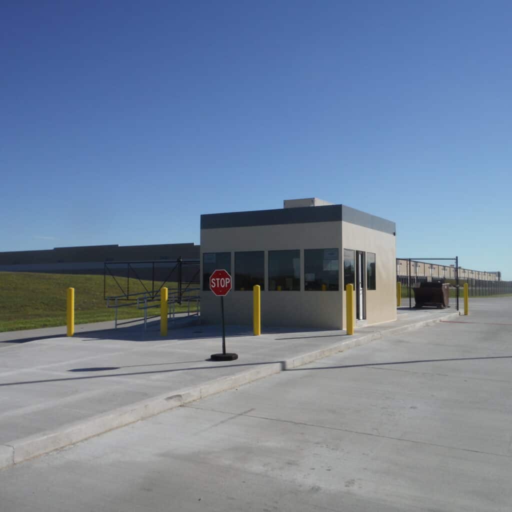Security building in front of a large distribution facility