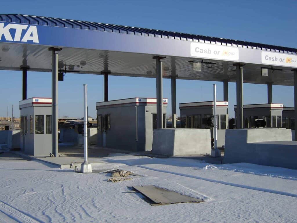 Snow-covered toll booths under a clear sky with signs reading 
