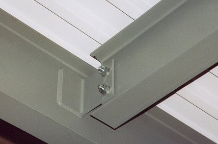 Two screws partially screwed into a transparent plastic bracket with Type 2 connections mounted on a white beam under a roof. The background shows slanted roof sections.