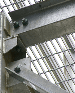 Close-up of a metal structure showing interlocking steel beams and bolts, with a grid pattern background, emphasizing industrial construction connections.