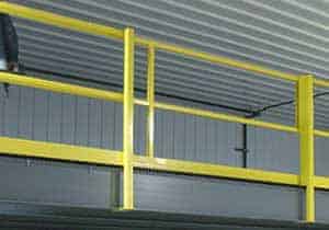 Yellow safety railings and a 6' gate against a backdrop of gray corrugated metal sheets and beams in an industrial setting.