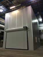 Large industrial overhead door closed within a warehouse setting, featuring a metallic finish and robust appearance under artificial lighting.