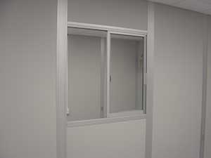 A simple interior image showing a small, closed window with white frames in a plain light gray wall, viewed from the side, illustrating the concept of a sliding window algorithm.