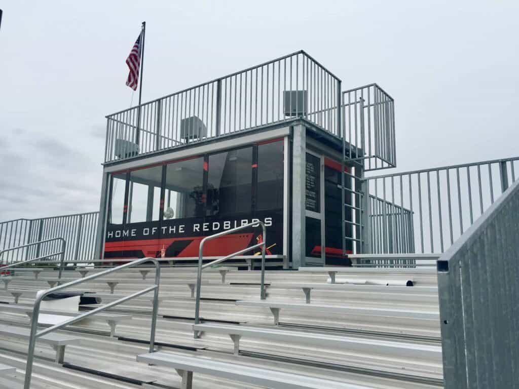 A modern, glass-enclosed sports media commentary box featuring 
