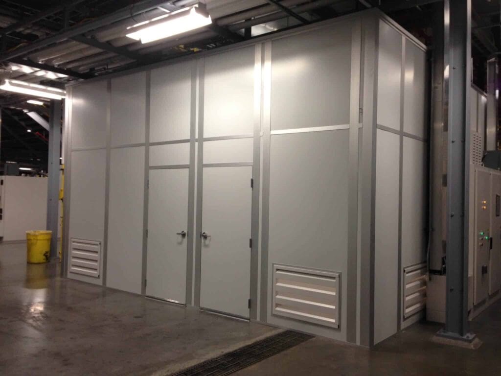 Large grey industrial doors on storage units in a well-lit warehouse setting with visible utility infrastructure and a yellow bucket to the side, enhanced for noise reduction.