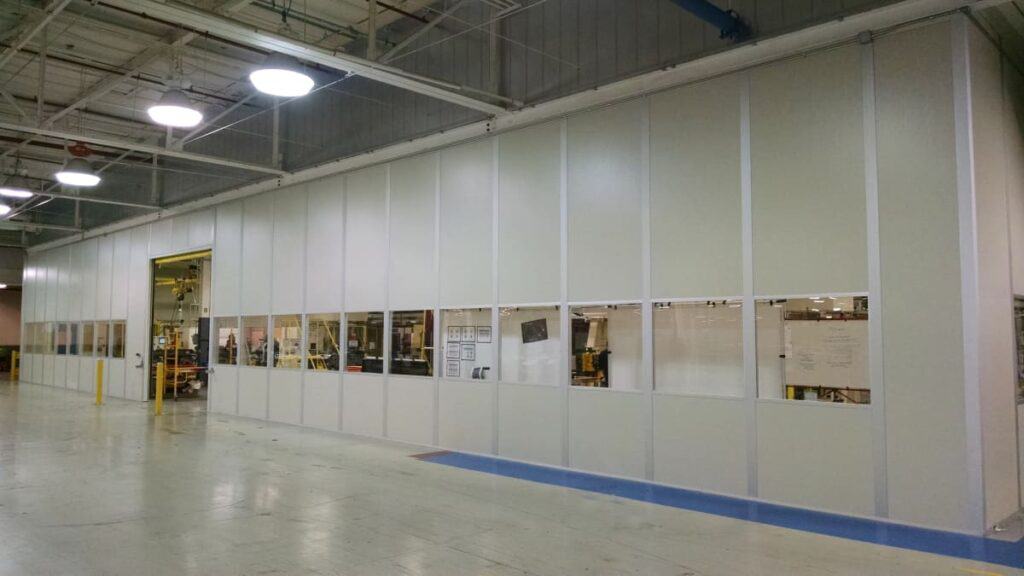Tall Modular Wall with Windows at Chrysler Interior of an industrial facility with tall walls and large windows showing machinery and workers, bright overhead lighting, and a clean, spacious floor.