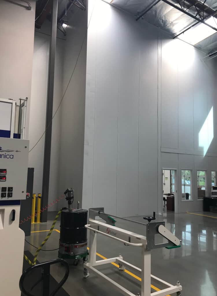 Tall Modular Wall on Factory Floor 13 Interior of an industrial facility with high ceilings, featuring a vertical lift and cleaning equipment near floor-to-ceiling modular walls.